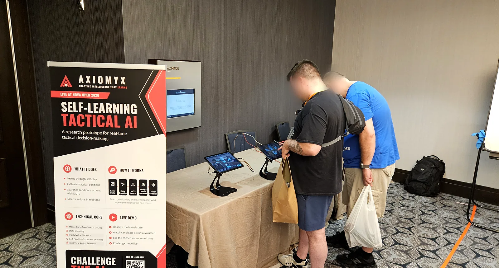 Two Nova Open attendees looking over an Axiomyx match together on the booth tablets.
